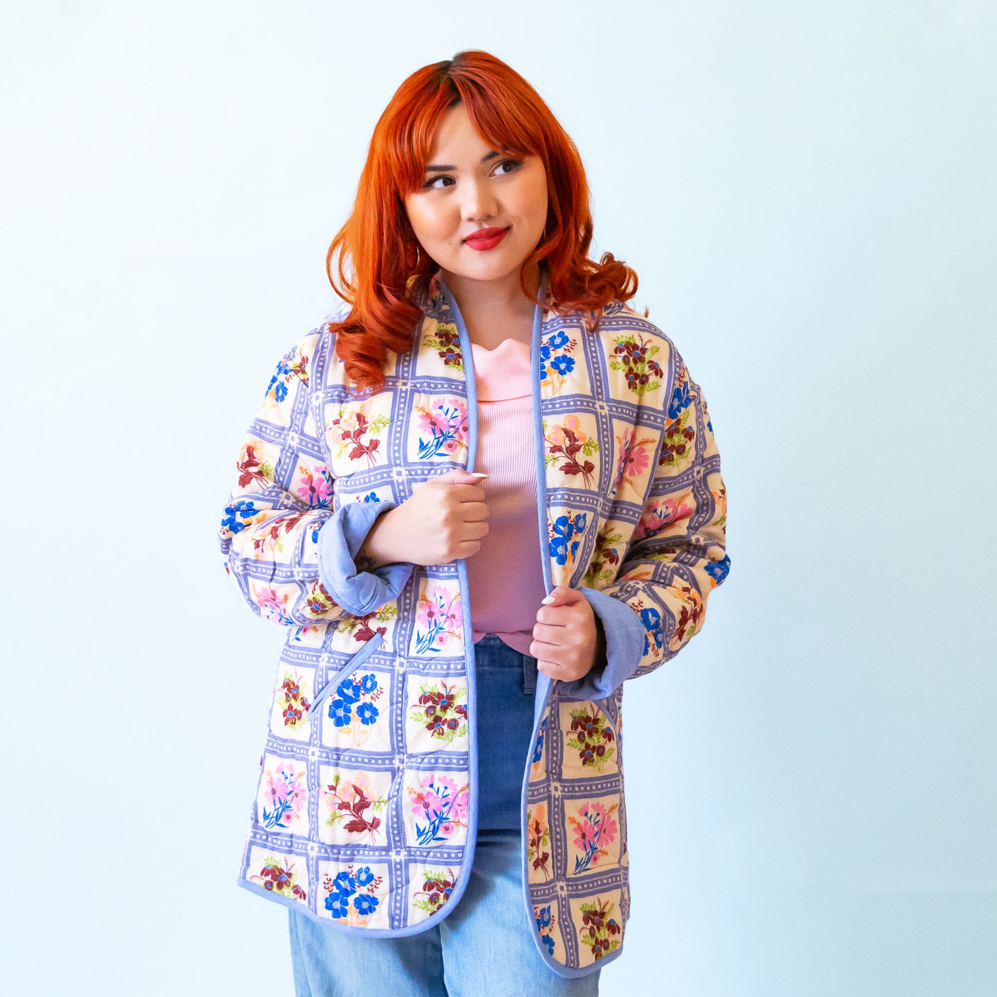 A multi colored quilted jacket with a floral print on one side and a blue solid color on the other. 