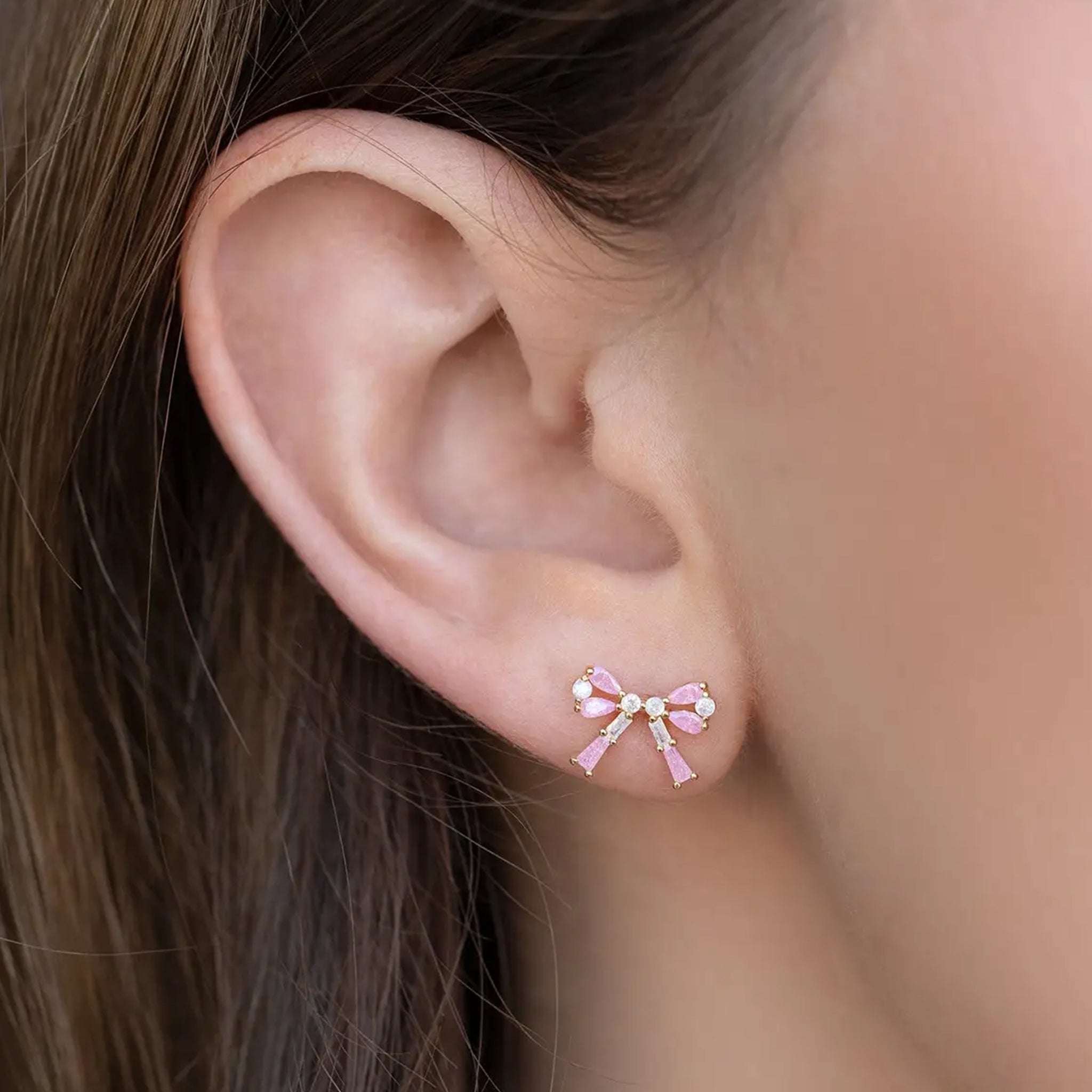 A pair of bow shaped stud earrings with pink and clear cz stones. 