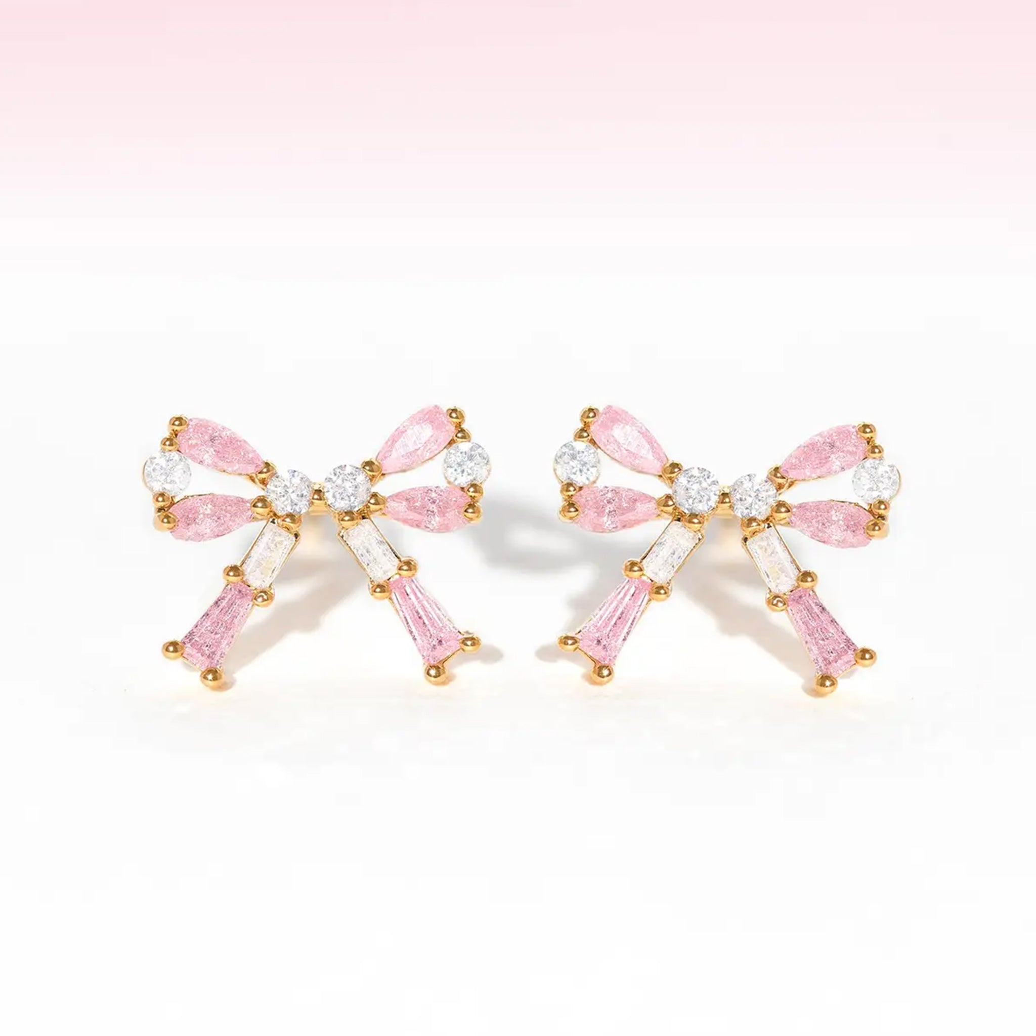 A pair of bow shaped stud earrings with pink and clear cz stones. 