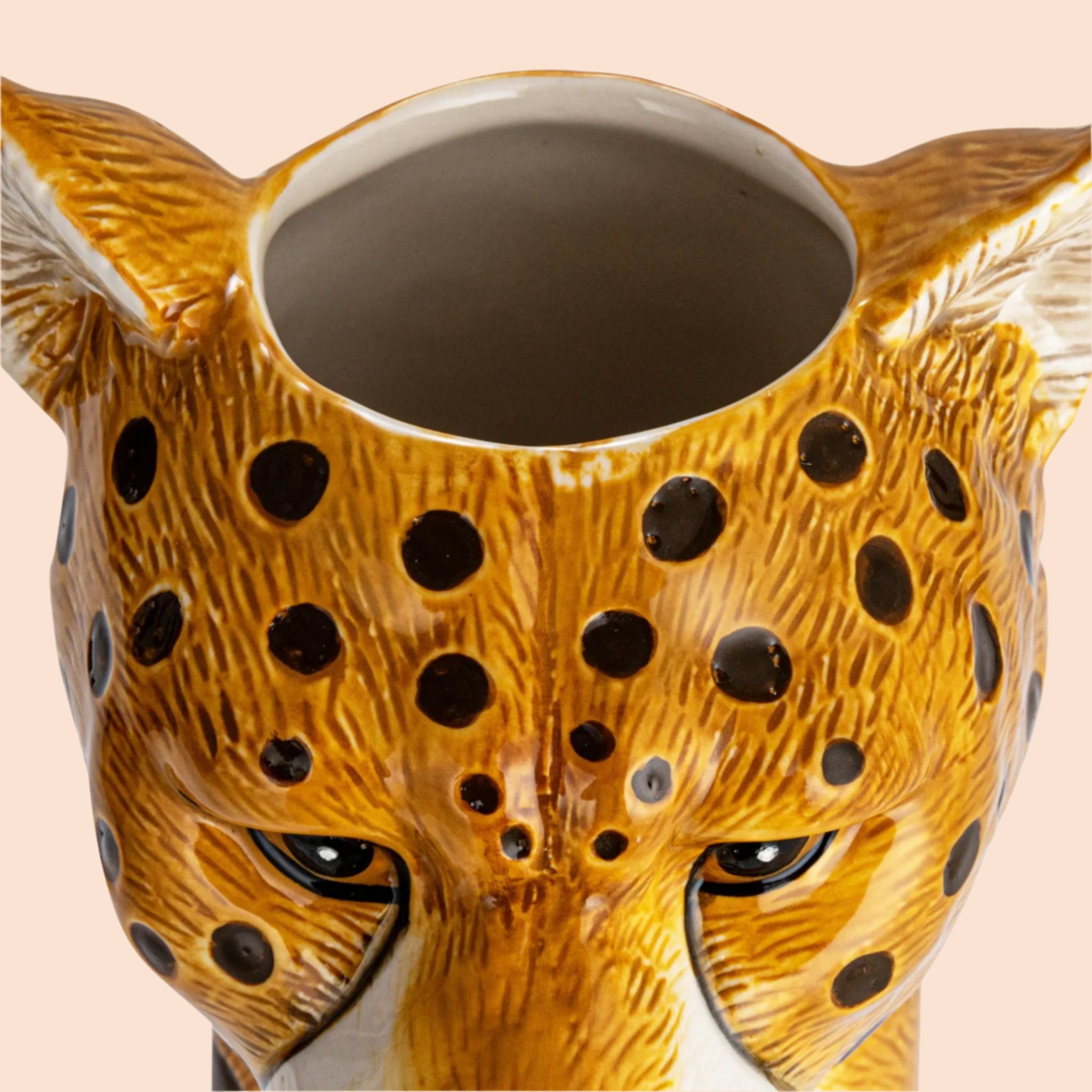 A cheetah head shaped ceramic vase with an opening at the top for an arrangement. 