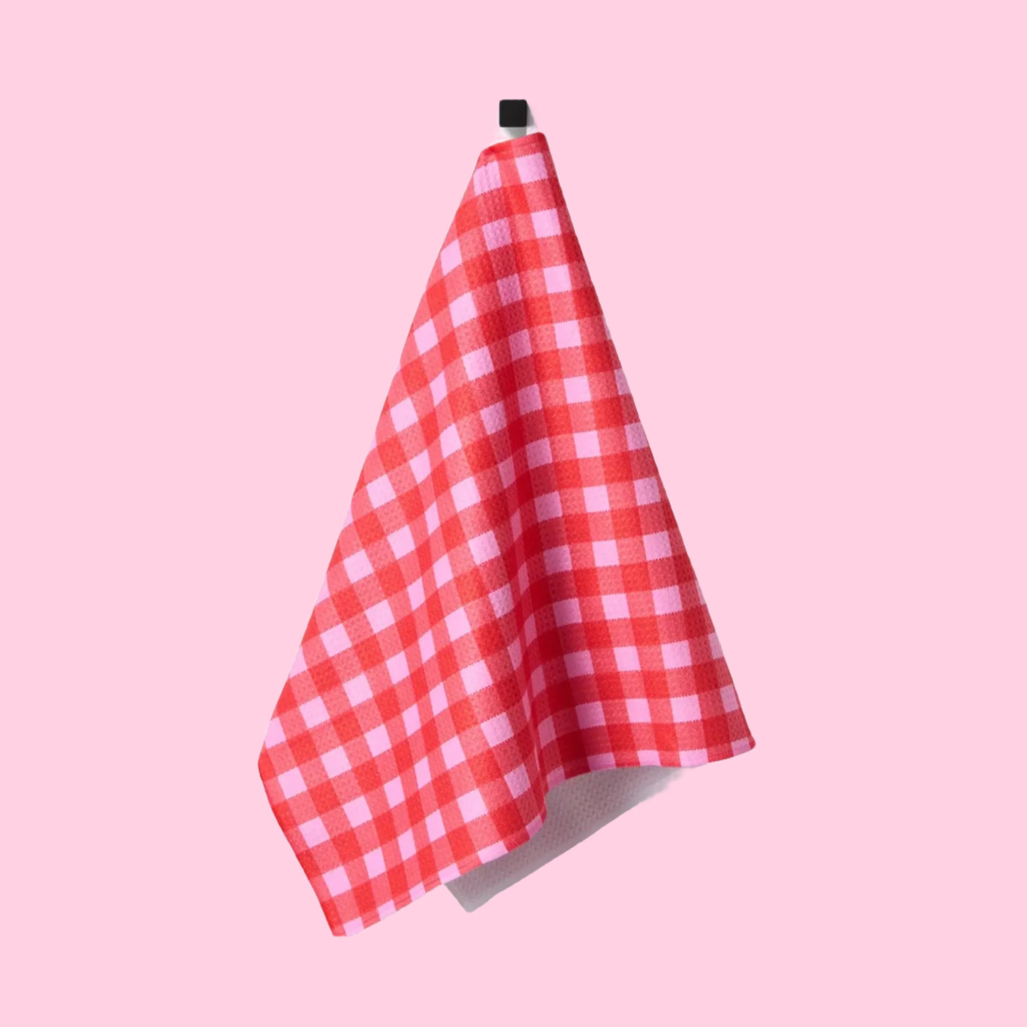 A red and pink gingham print tea towel with a waffle weave.