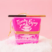 A pink glass ornament made to look like a Chinese to-go box with a pair of chopsticks across the top.