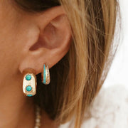 Chunky gold hoop earrings with three blue opal stones. 