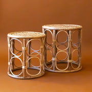 A set of two rattan nesting tables with a circle design around the edges. 