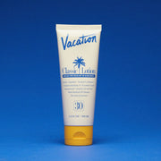 A white squeeze tube of sunscreen with a yellow lid and a blue text that reads, "Vacation Classic Lotion SPF 30" along with a blue palm design in the center.