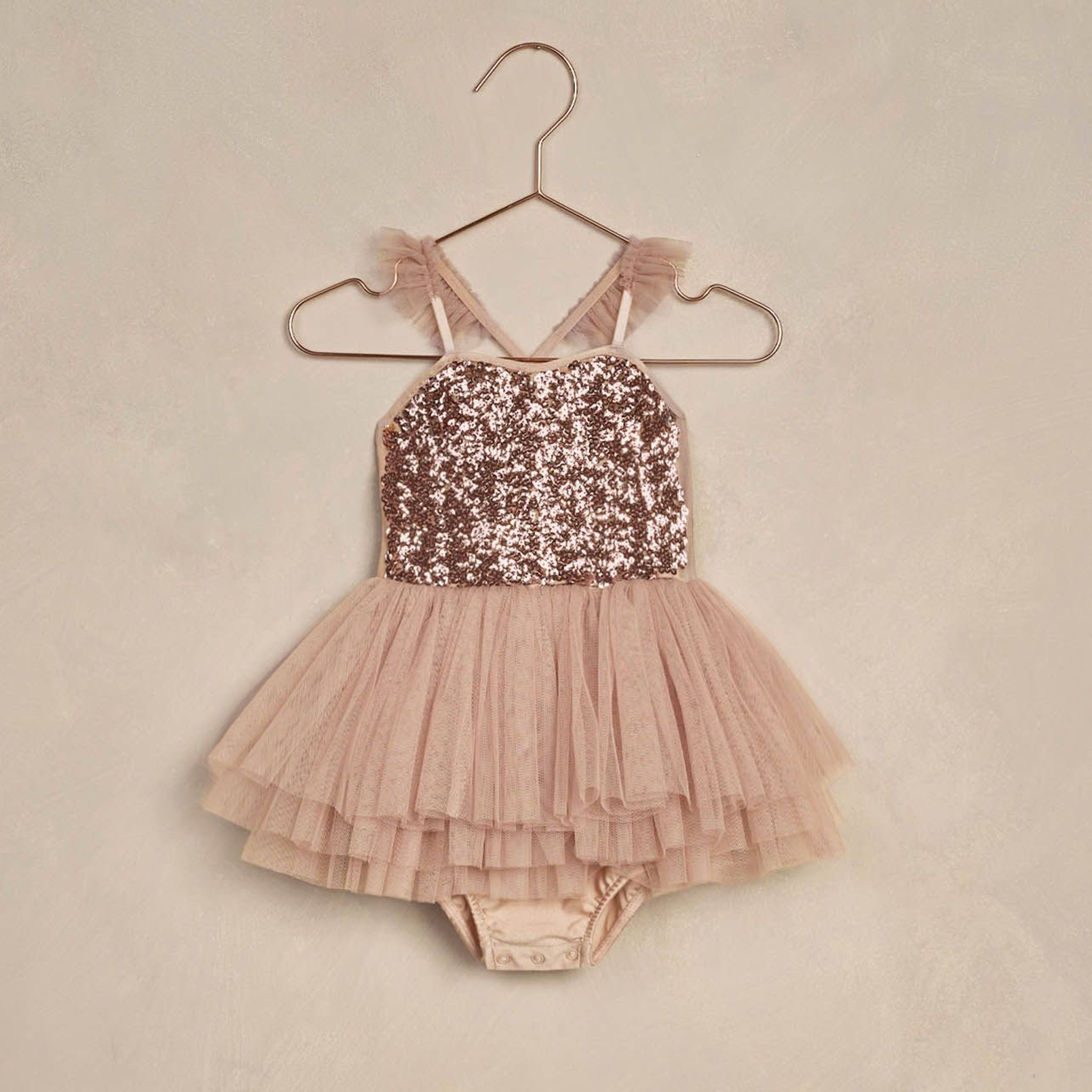 A dusty pink and rose gold sequin tutu with ruffle back strap details and snap closure.