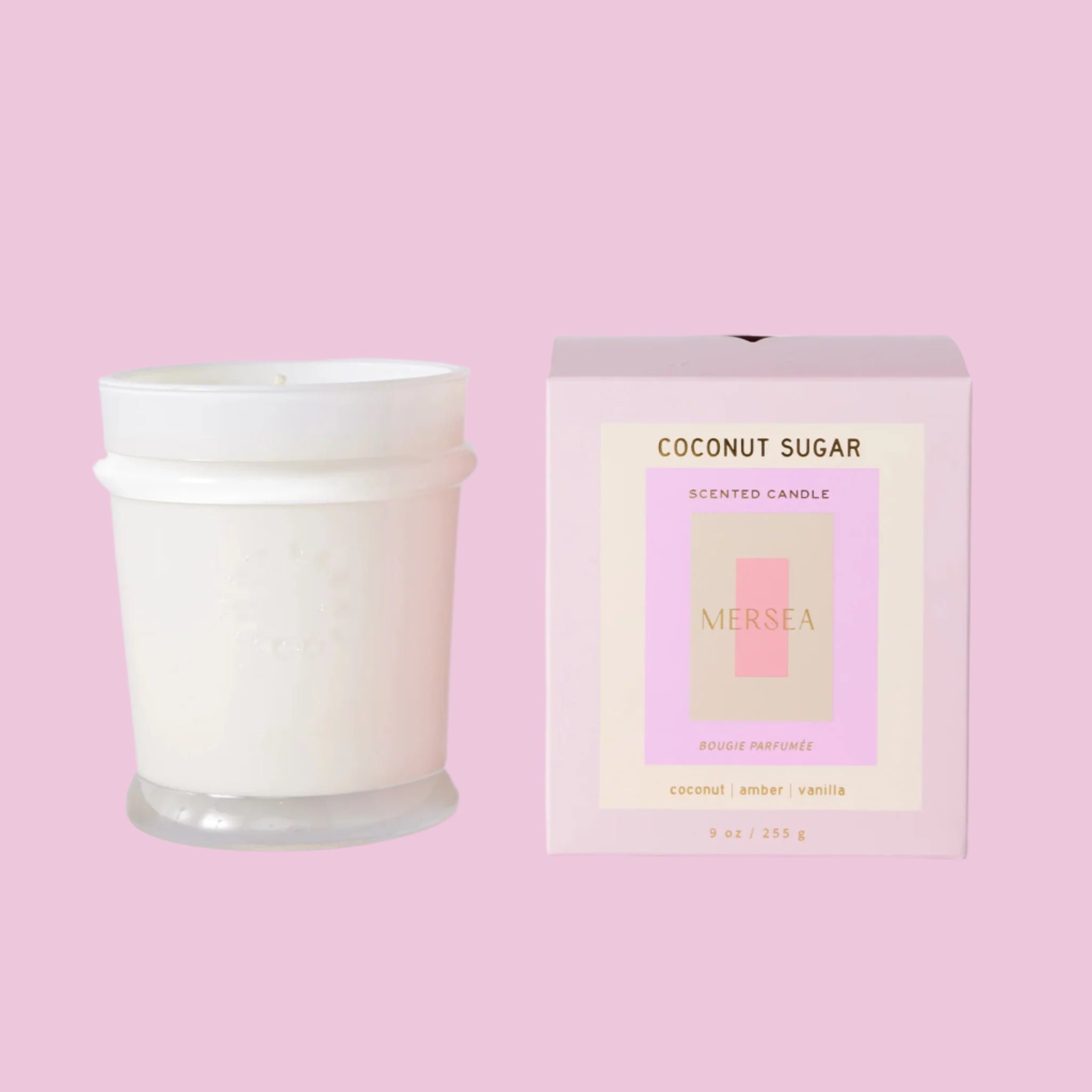 A white candle with a cool toned pink box with text that reads, 'Coconut Sugar Scented Candle'. 