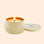 On an ivory background is a round tin candle with it's lid to the right side.  The flame of the candle is lit.  The lid of the jar reads "Voluspa Coconut Papaya"