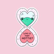 A pink heart shaped compact sticker with a green frog in the reflection and text that reads, 'Who Is That Hottie?'.