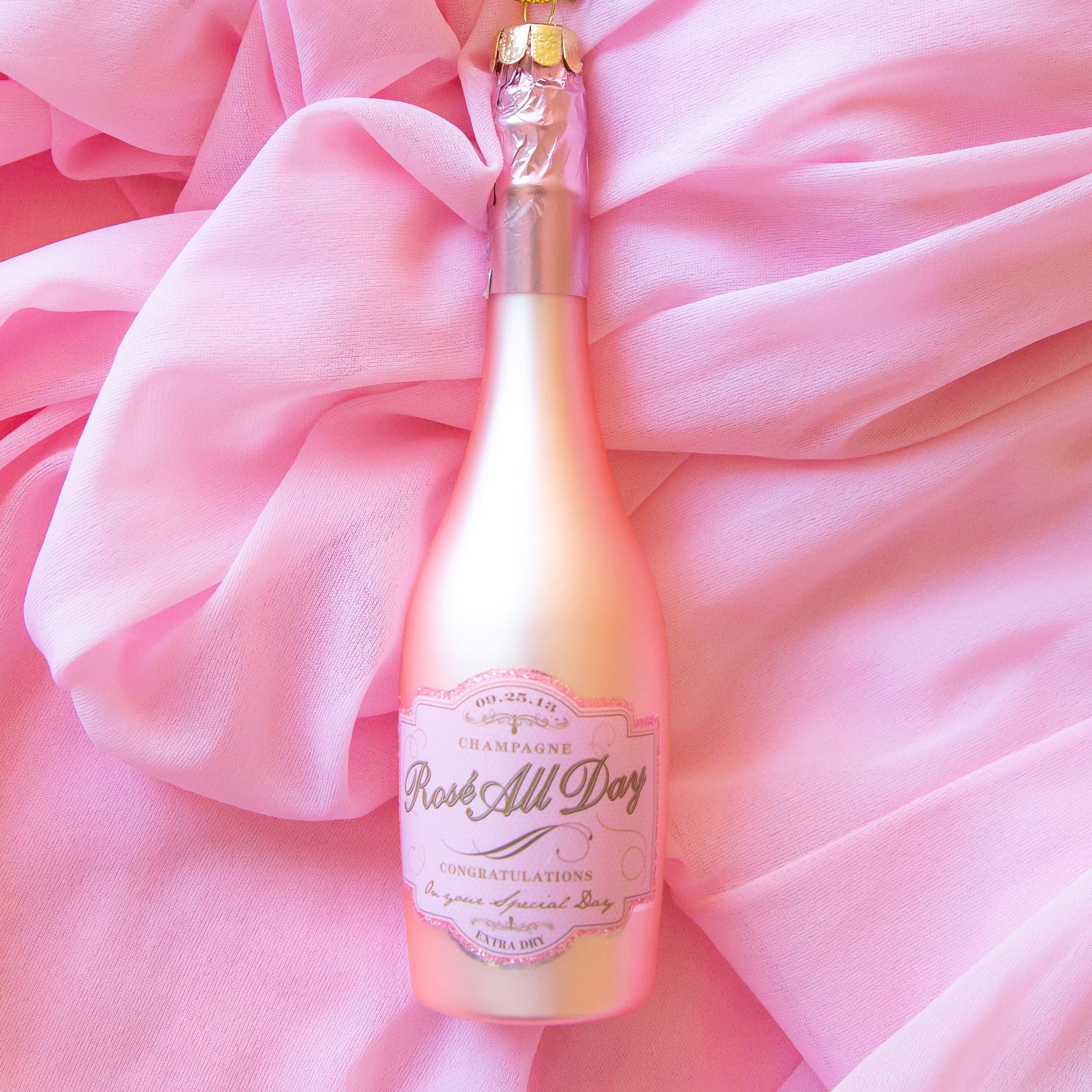 A pink champagne bottle shaped ornament with a label that reads, 'Rose All Day'. 