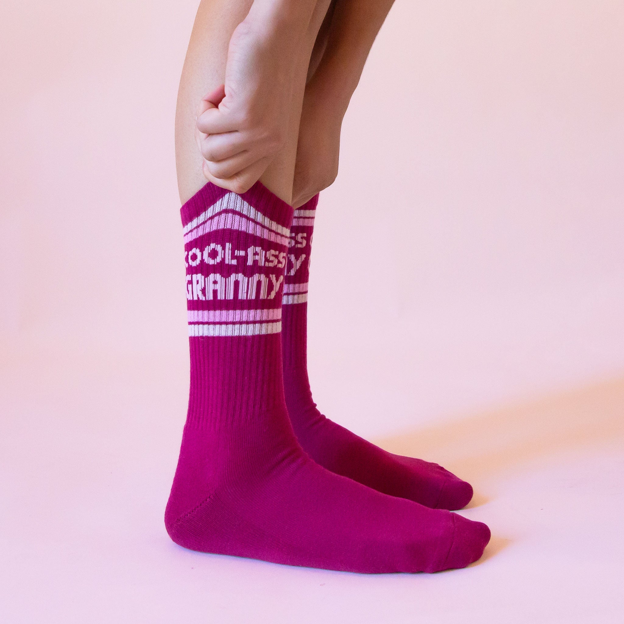 Dark pink ribbed crew socks that read, &#39;Cool-Ass Granny&#39; on the ankle of the socks in light pink letters. 