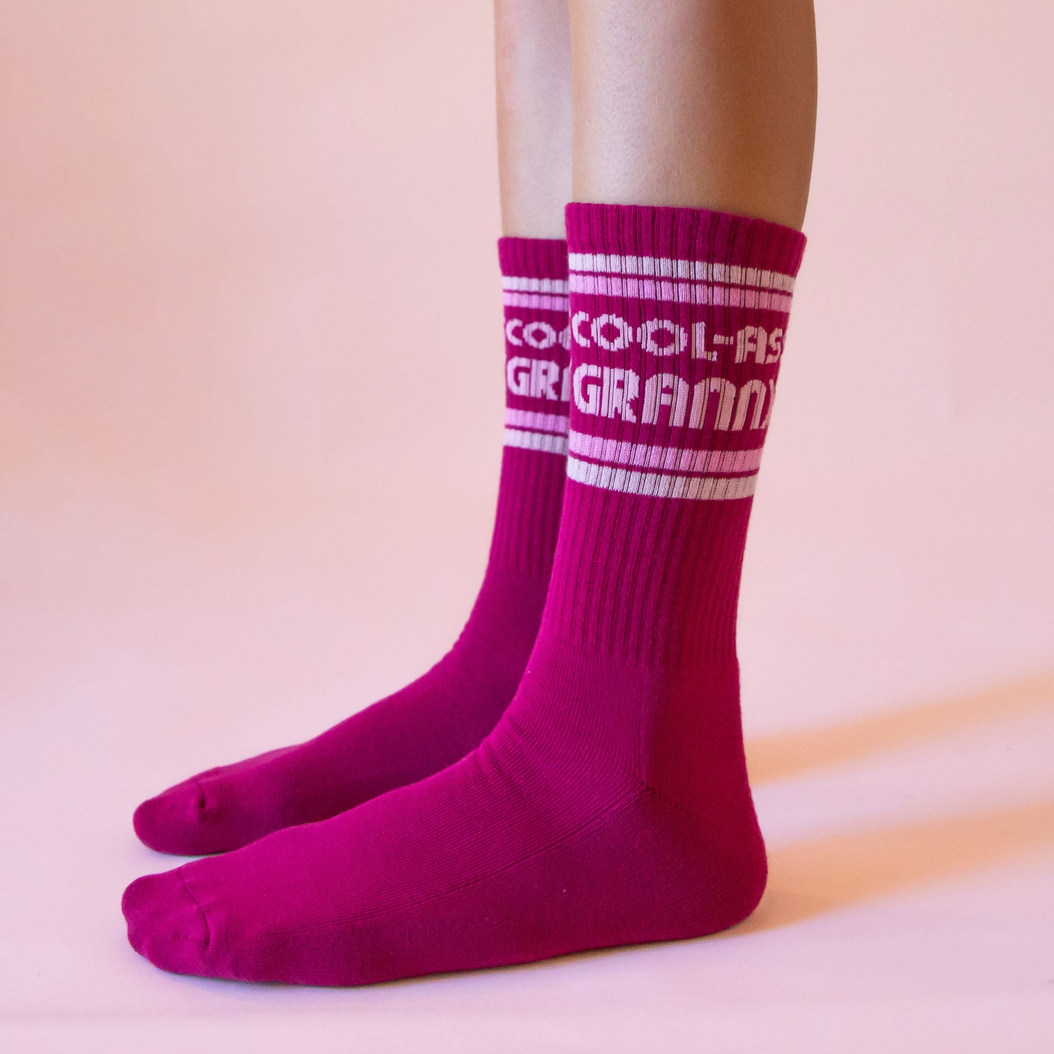 Dark pink ribbed crew socks that read, &#39;Cool-Ass Granny&#39; on the ankle of the socks in light pink letters. 