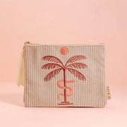 A greyish tan corduroy pouch with a single zipper going across the top and a palm tree, snake and sun graphic in the center.