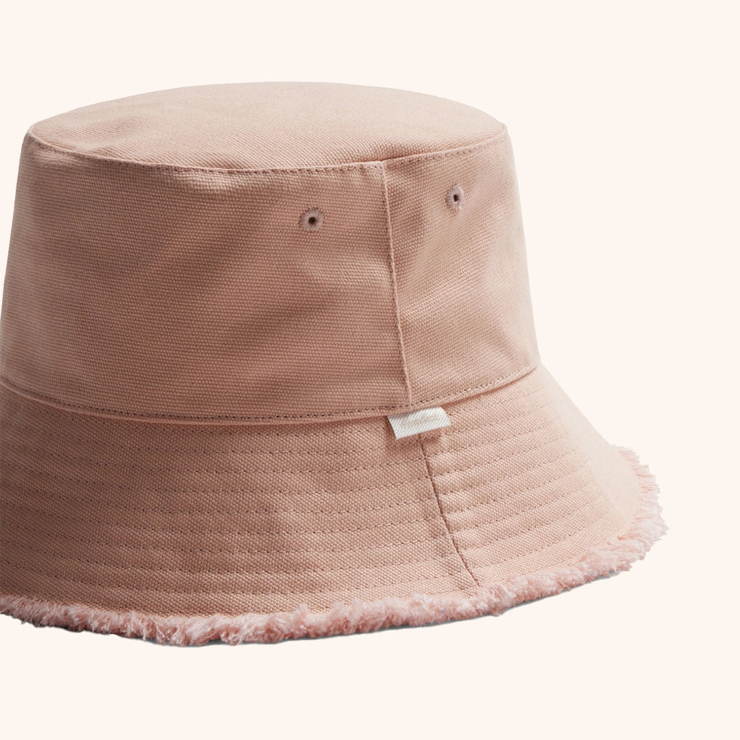 On a white background is a light pink bucket hat with a soft frayed edge. 