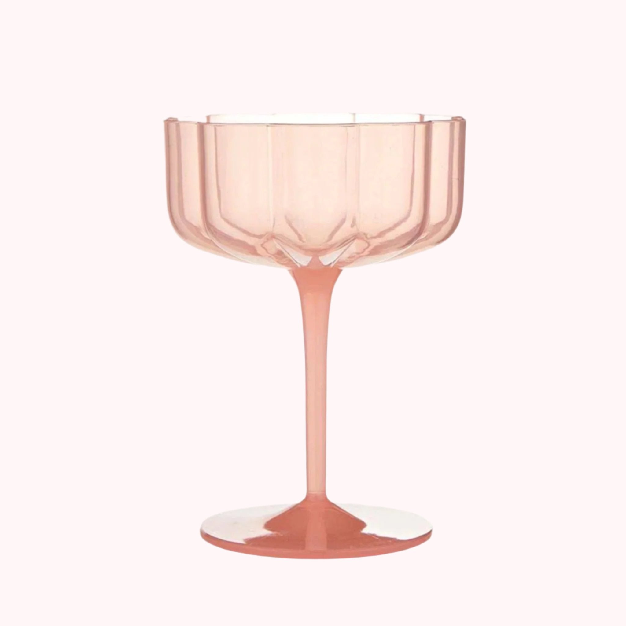 A light peachy pink coupe glass with a wavy edge. 