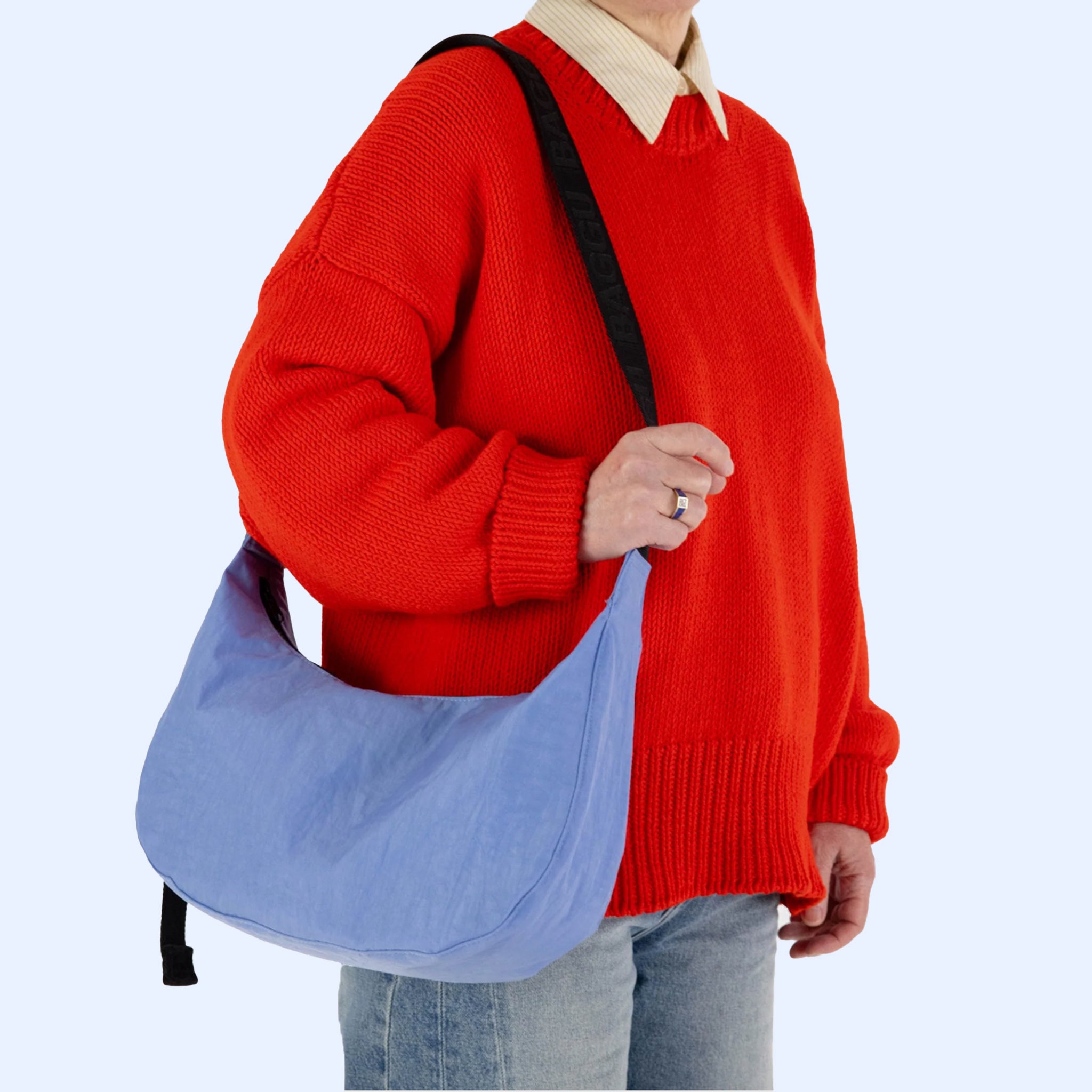 A blue nylon crescent shaped handbag with a black adjustable strap.