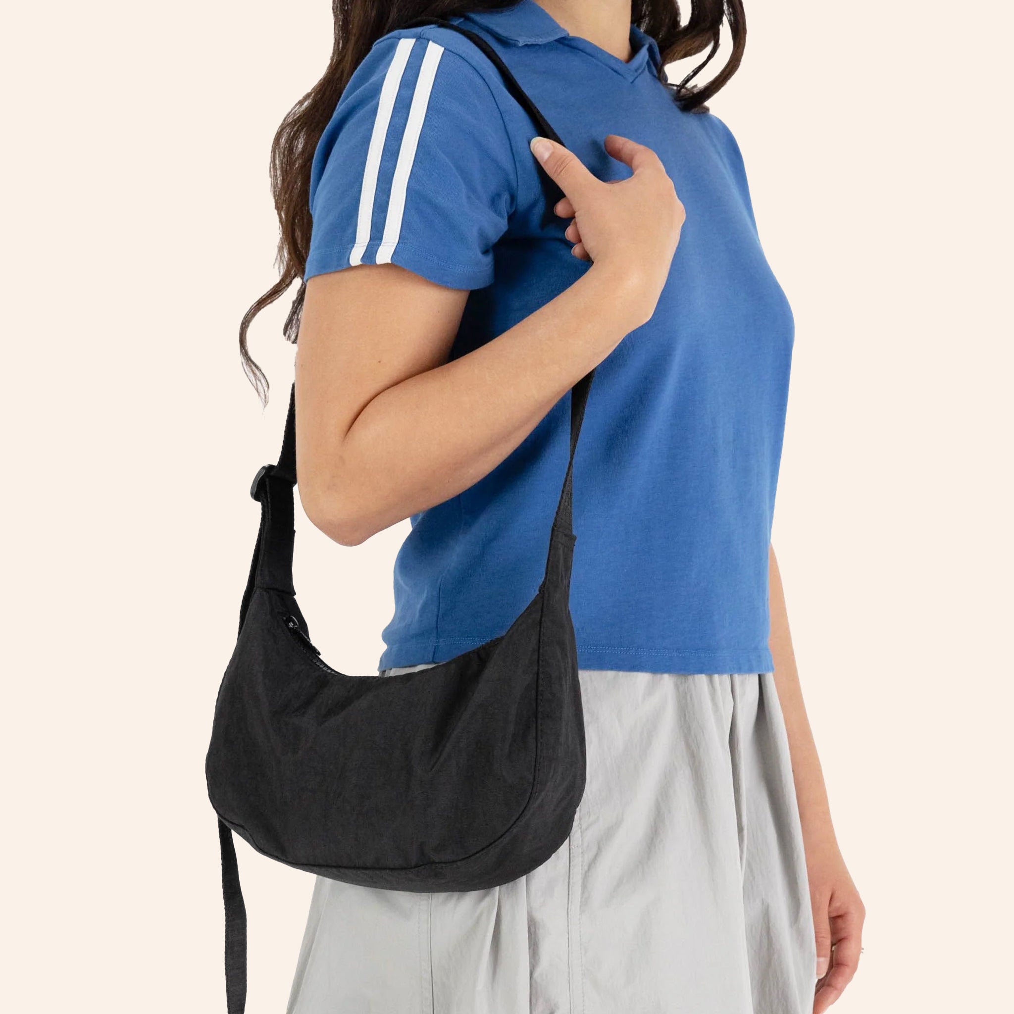 A small crescent shaped nylon shoulder bag with an adjustable strap to make it crossbody.
