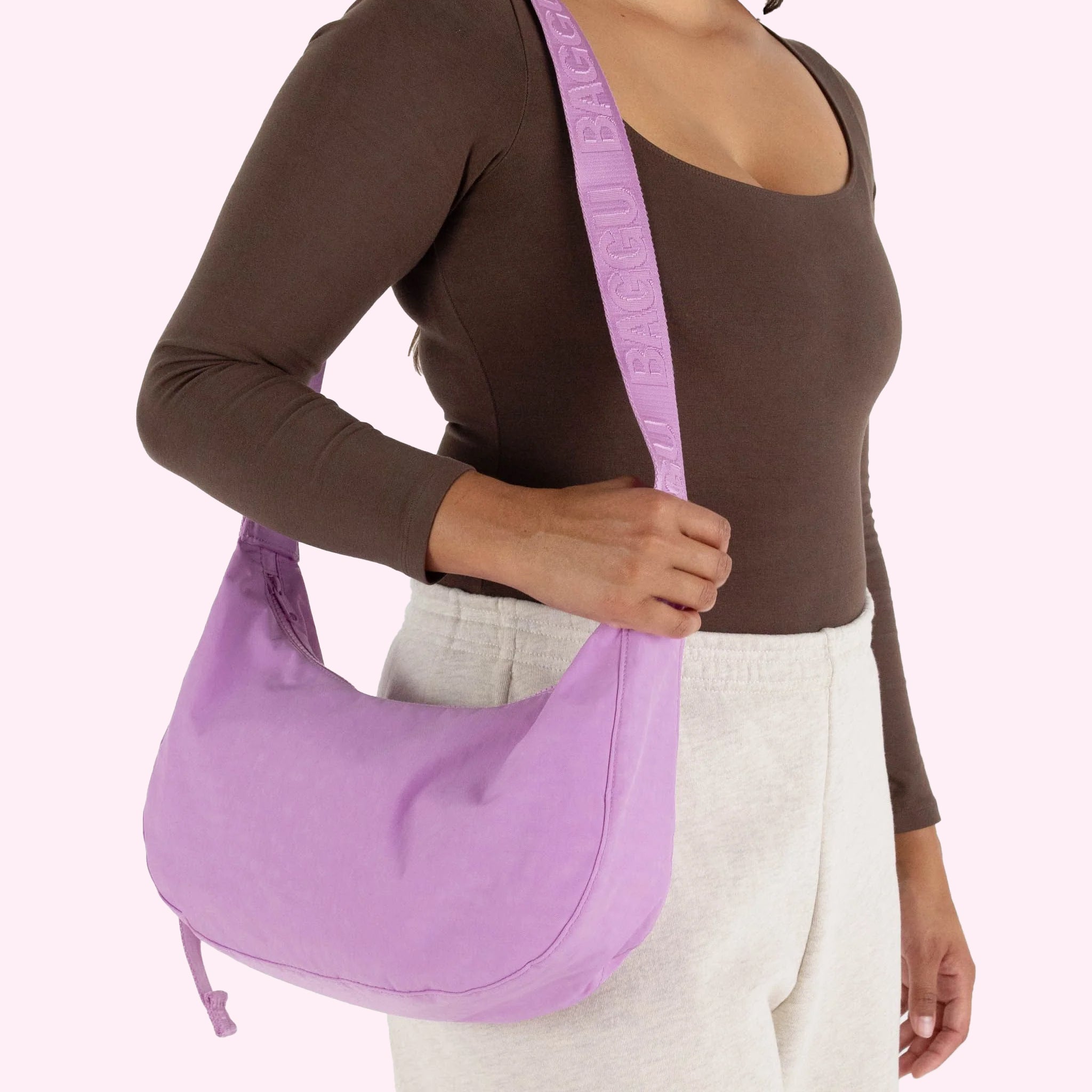 A pinkish purple crescent shaped nylon handbag with an adjustable strap.