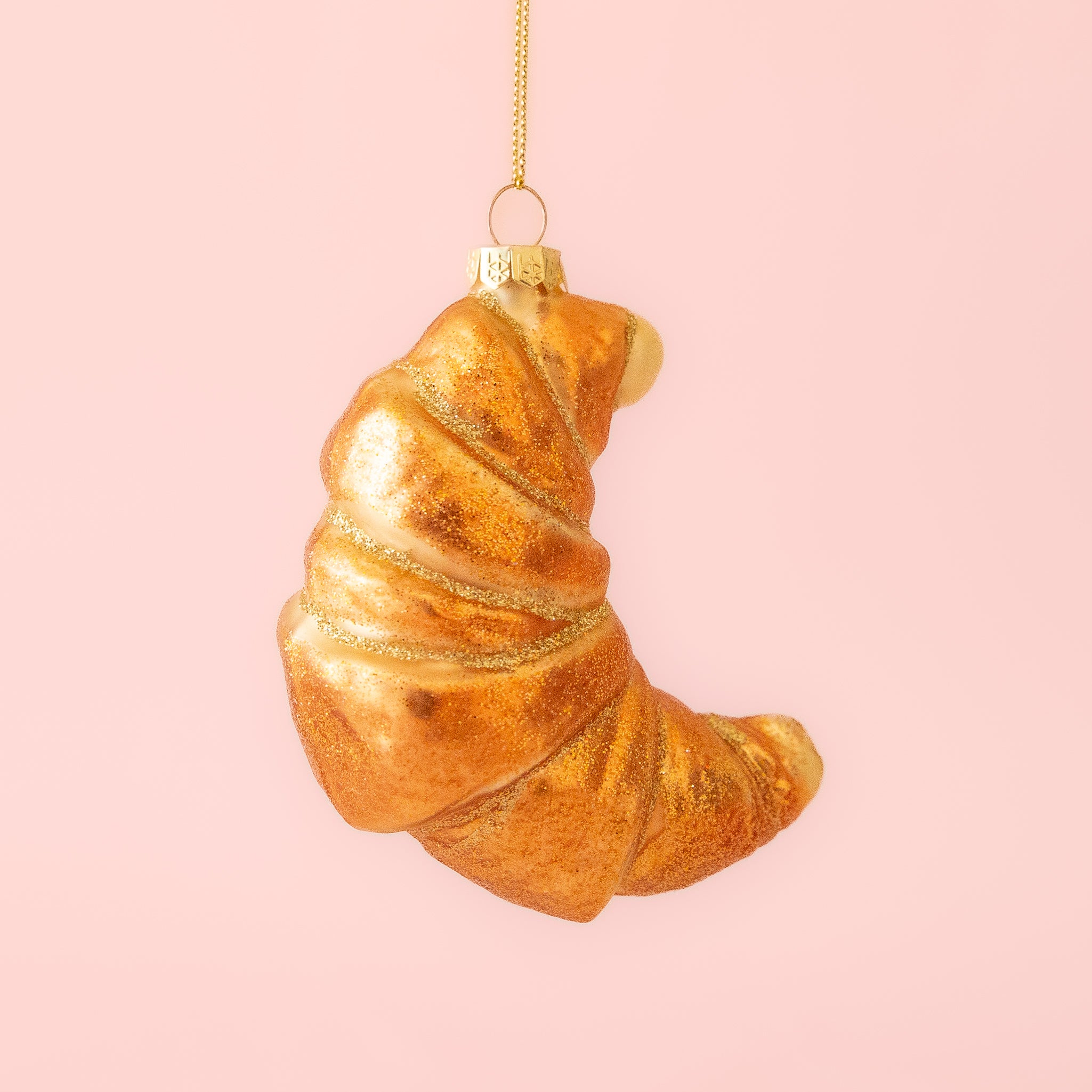 A croissant shaped glass ornament with glitter details. 