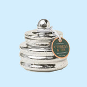 A silver glass jar candle with a lid. 