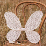 A natural colored pair of costume wings with an embroidered daisy pattern all over and elastic arm straps. 