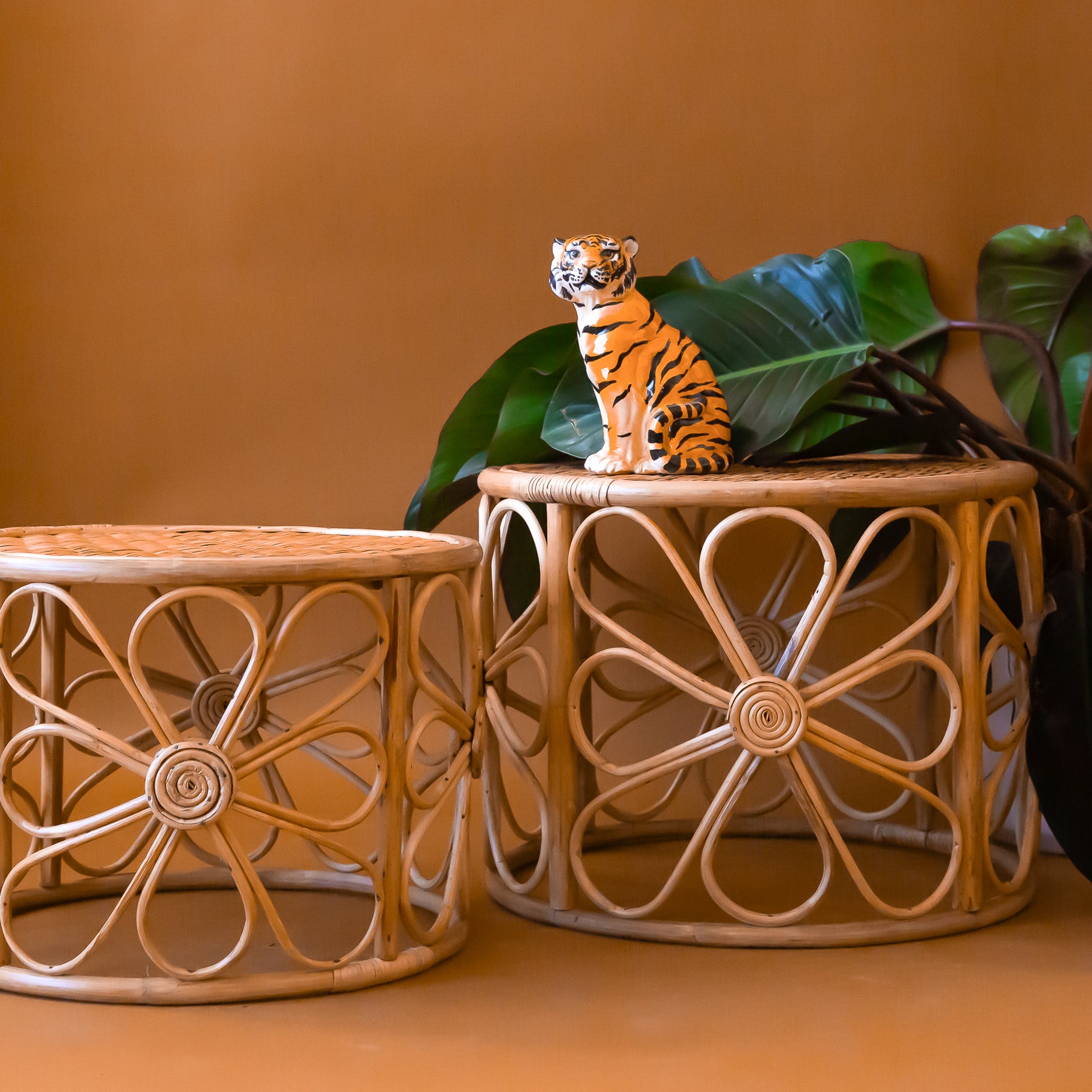 Three rattan nesting tables with a daisy design around the edges.