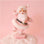 On a pink background is a Santa figurine with a pink flocked suit and white furry details. 