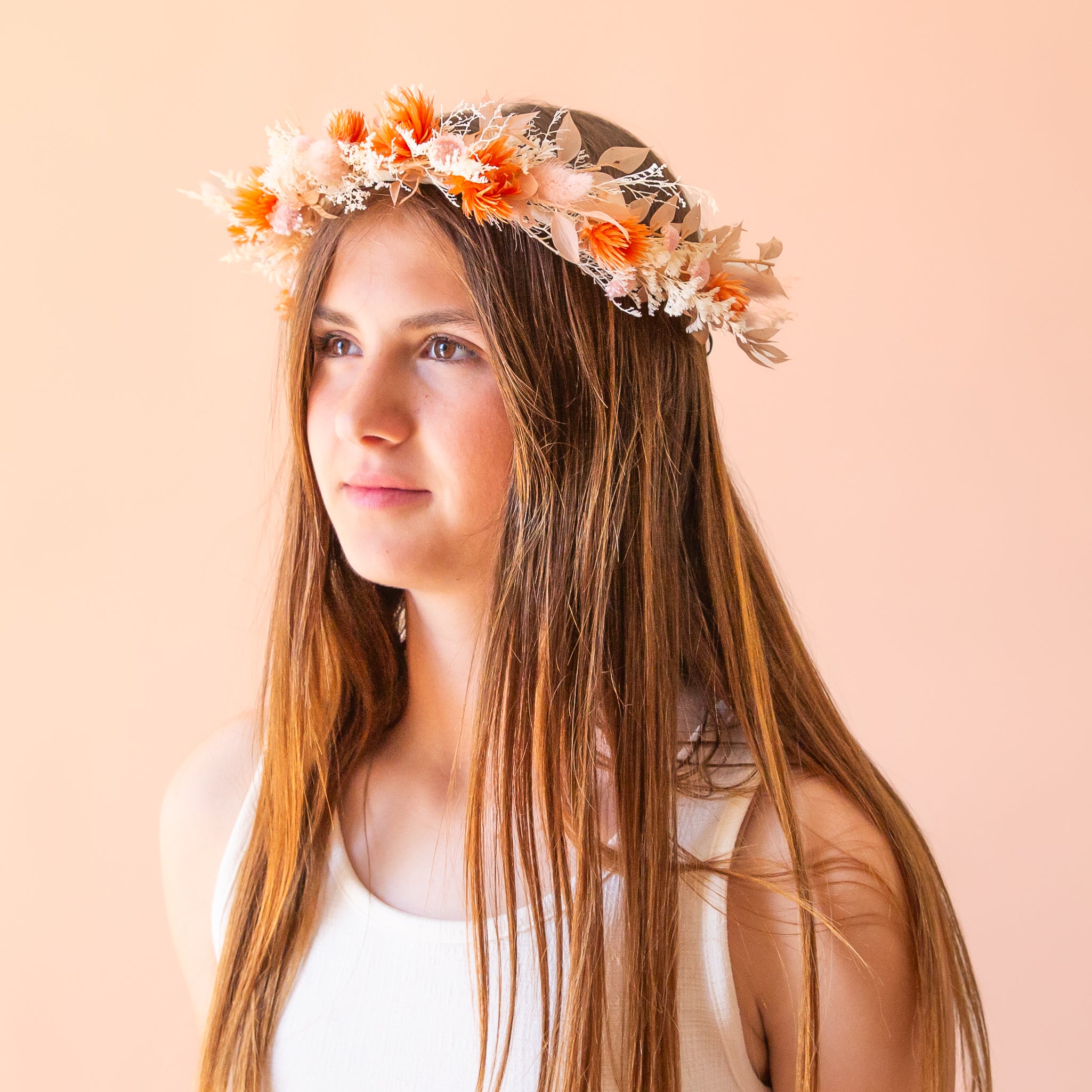 A flower crown made up of orange and neutral dried florals with a ribbon tie detail on the back. 