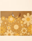 On a white background is a brown gift bag with yellow daisies. 