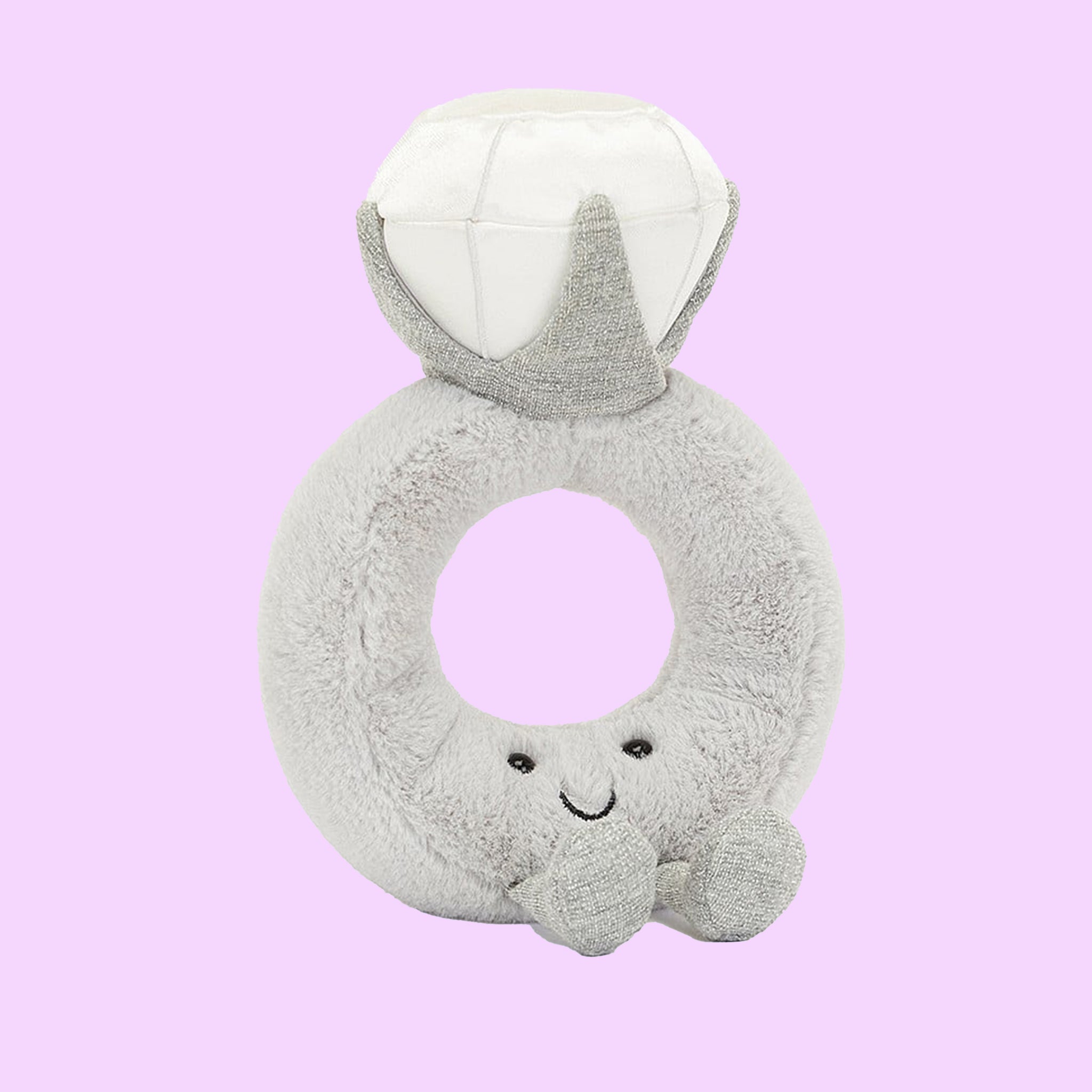 A grey stuffed toy in the shape of a diamond ring with a grey band and a white diamond shape along with a smiling face and feet on the front.