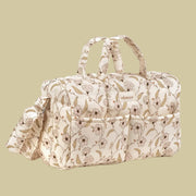 A neutral diaper bag from the brand minikane with a light pink and light green floral print. 