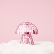 On a pink snowy background is a pink disco mushroom ornament.