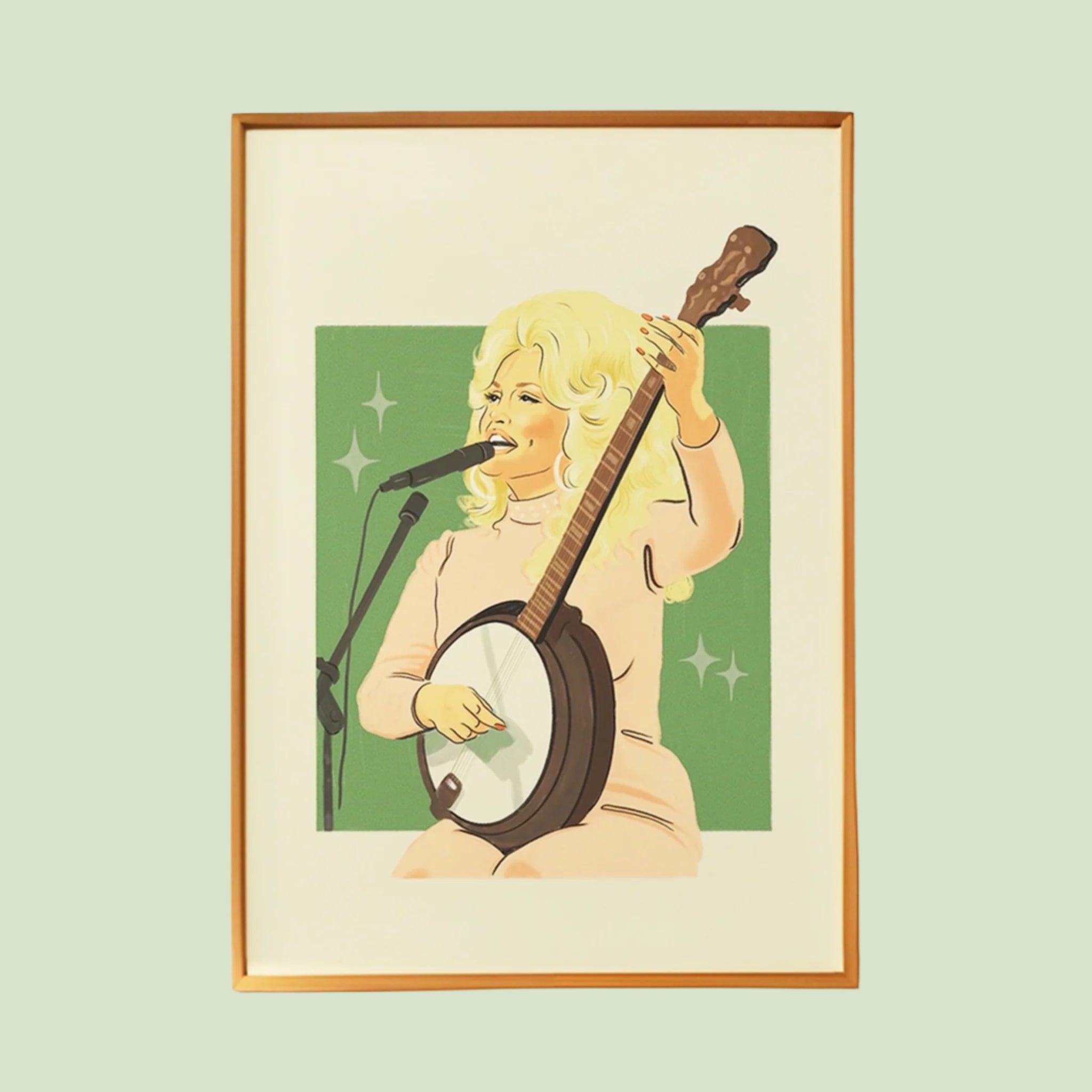 An art print of Dolly Parton signing and holding her banjo with a green background and her in pink. Frame not included. 