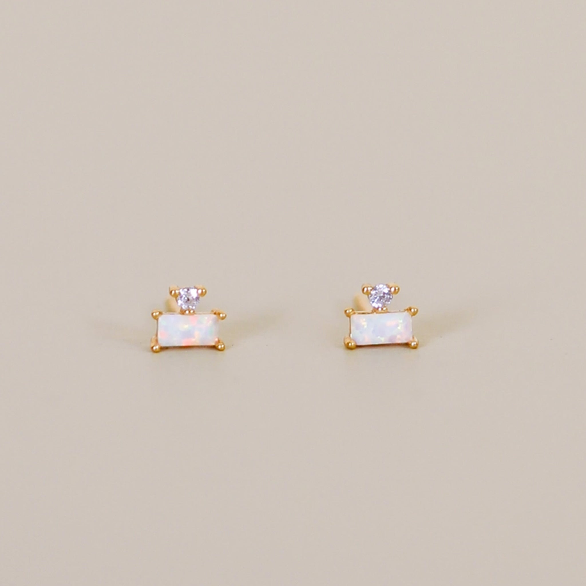 A pair of stud earrings with a baguette and circle shaped stone. 