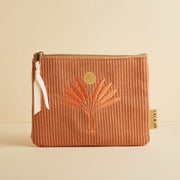 A dusty pinkish orange corduroy pouch with a desert palm and sun design.