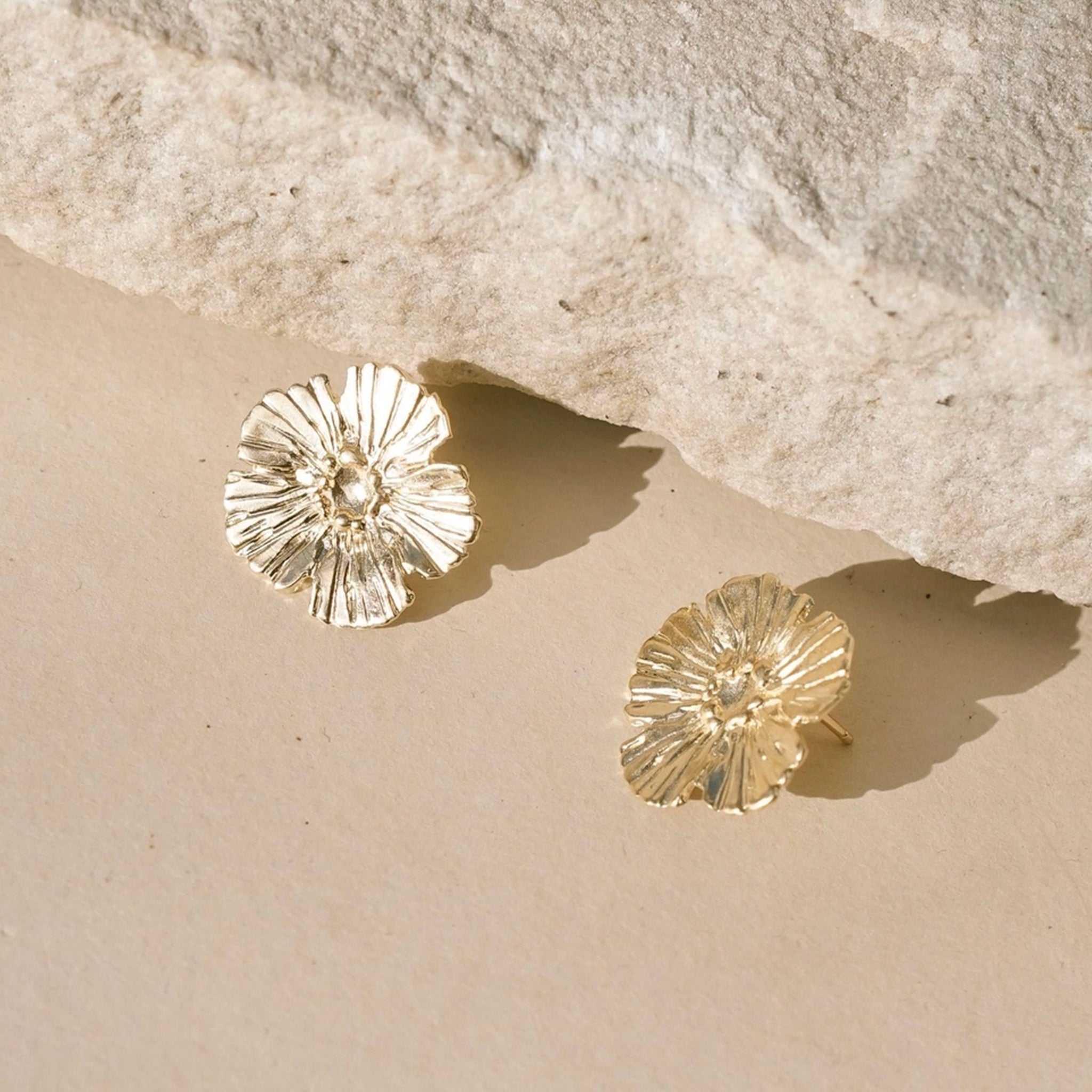 A gold pair of flower shaped earrings. 