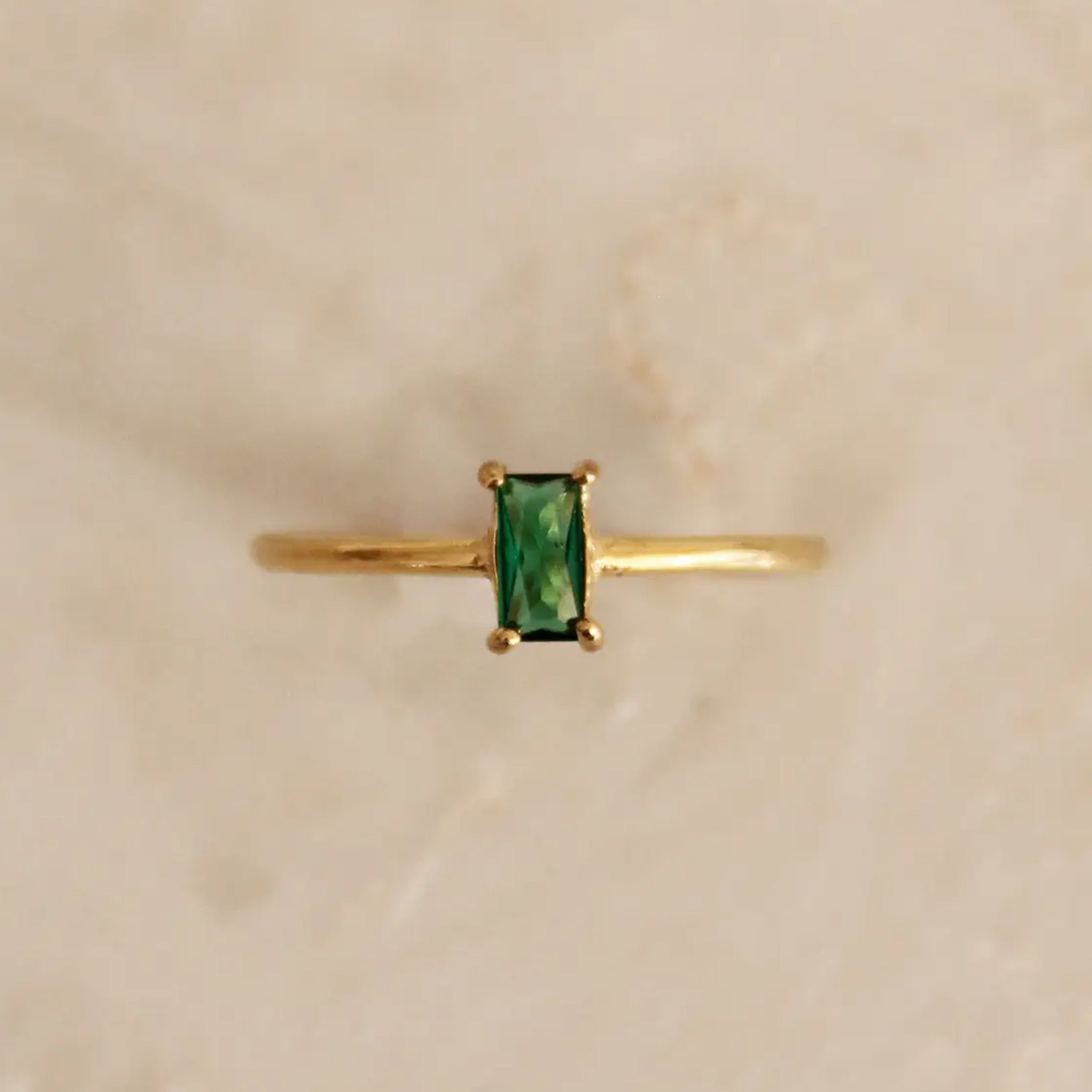 A gold band ring with green emerald cz stone in the center. 