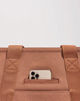 On a white background is a brownish/tan tote bag for carrying pets with two straps and a padded black bottom.