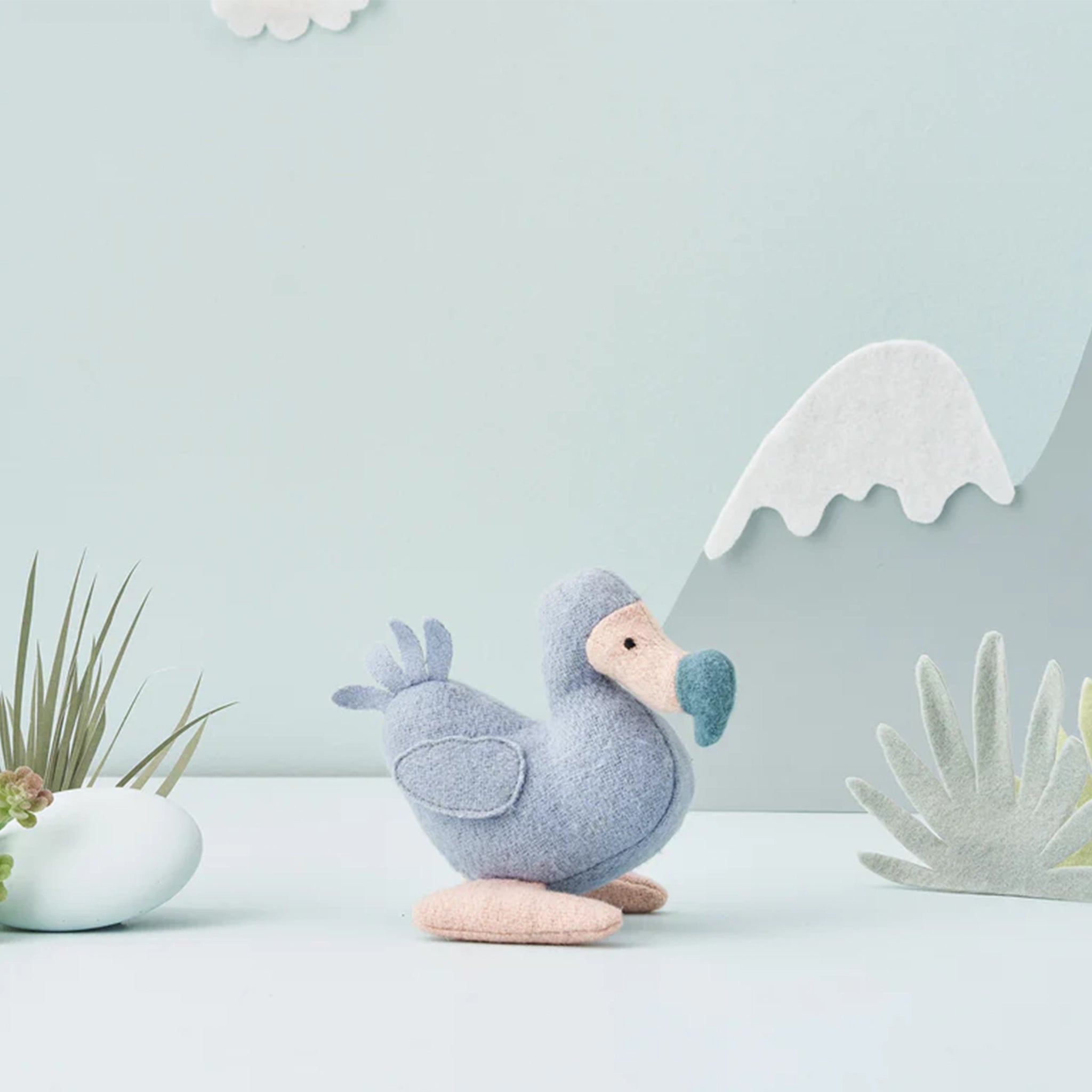 On a light blue background is a blue dodo bird stuffed animal. 