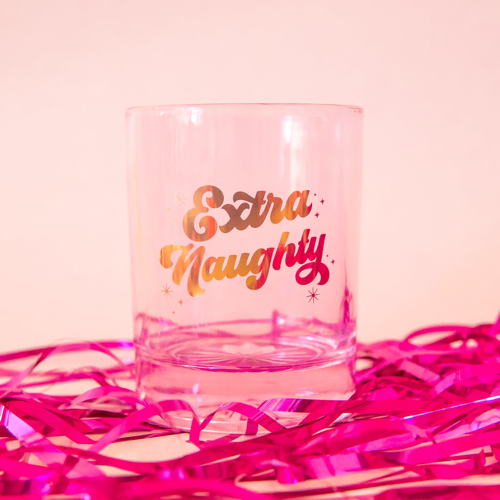 pink glass tumbler with gold script font that says &quot;extra naughty&quot;