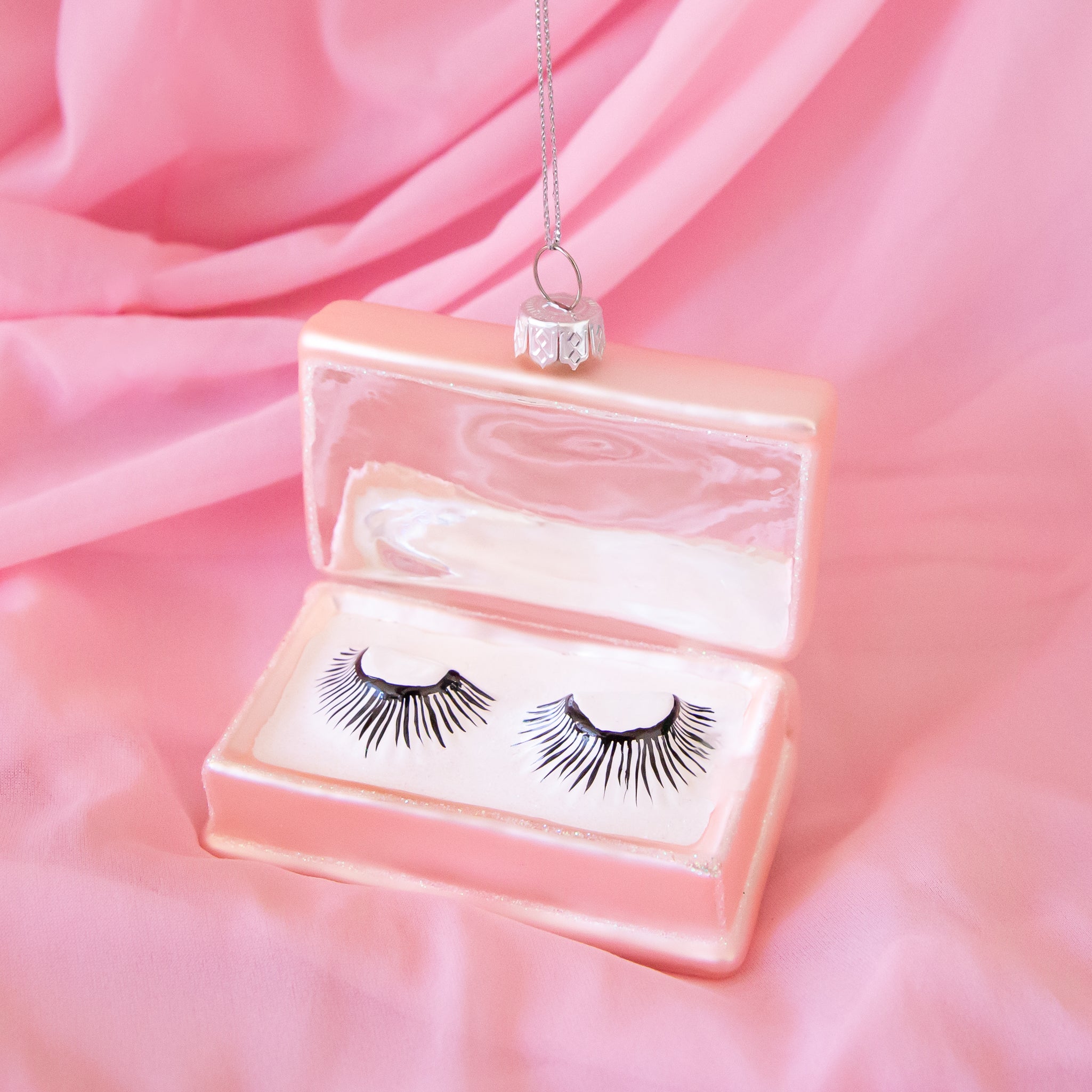 A pink fake eyelash box shaped glass ornament. 