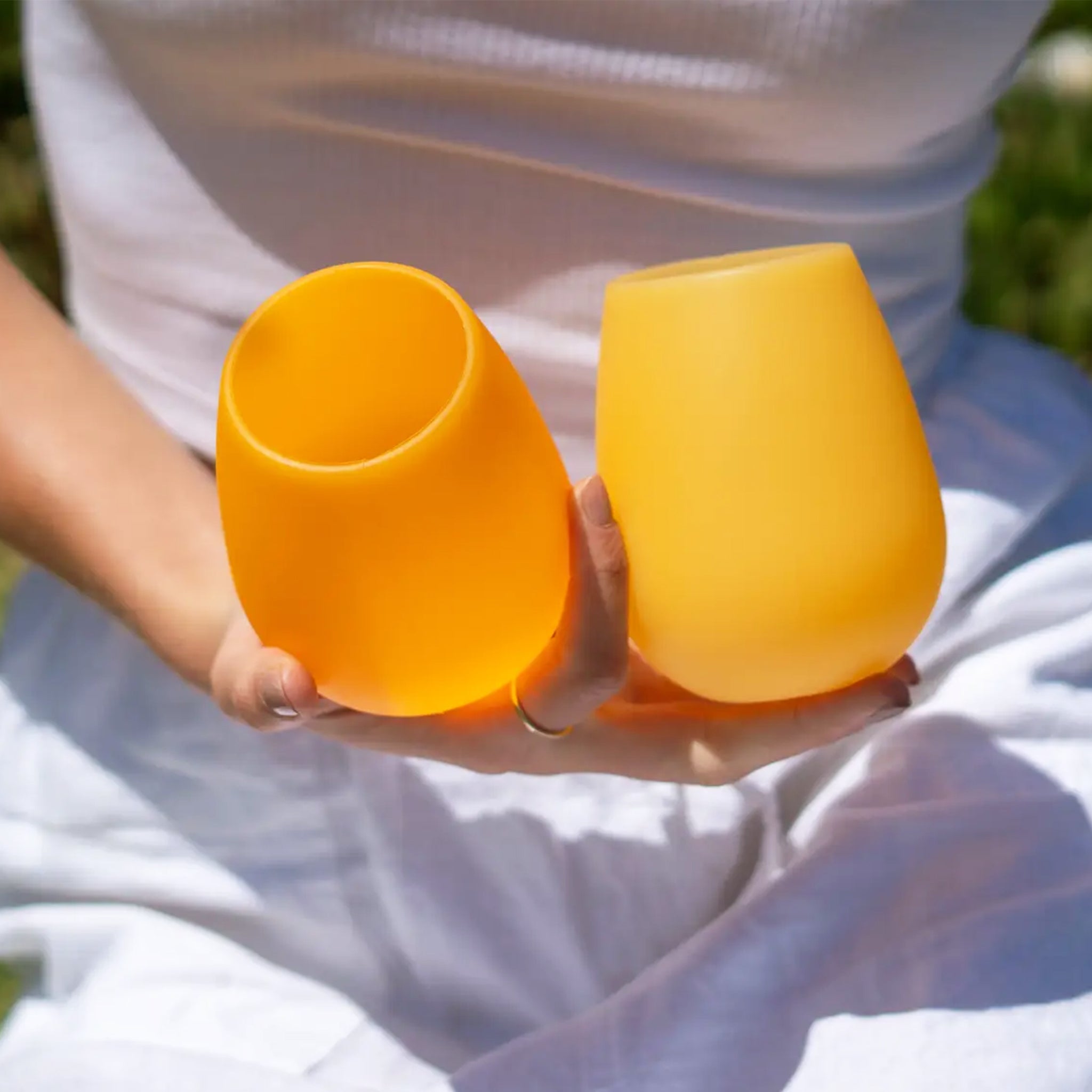 A pair of stemless silicone cups, one light yellow and the other darker.