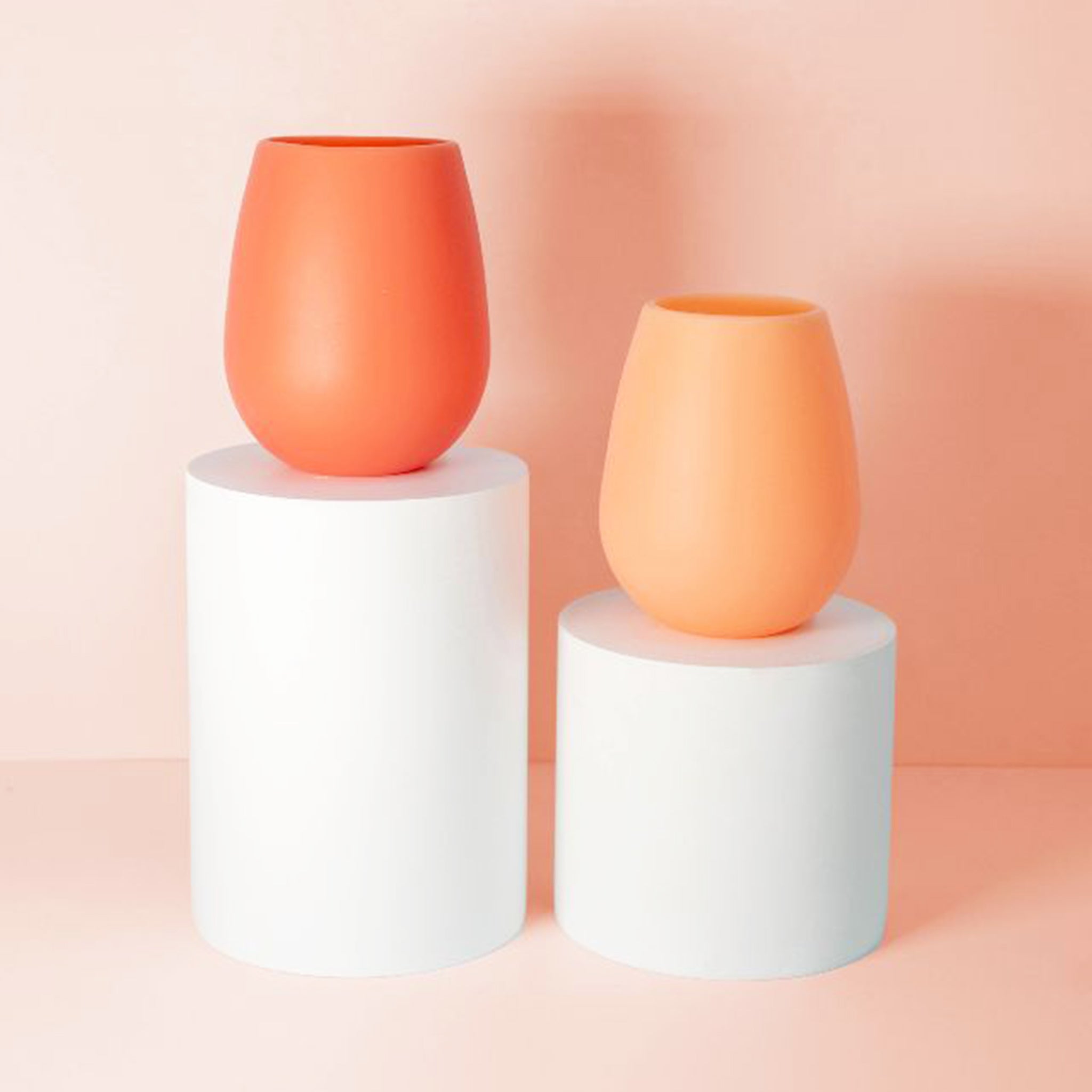 Two peachy pink and terracotta silicone stemless cups. 