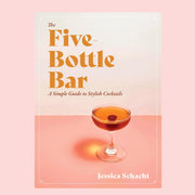 A cream and light pink book cover with a photograph of a coupe cocktail glass filled with an orange liquid along with orange text in the top left corner that reads, "The Five Bottle Bar, A Simple Guide to Stylish Cocktails".