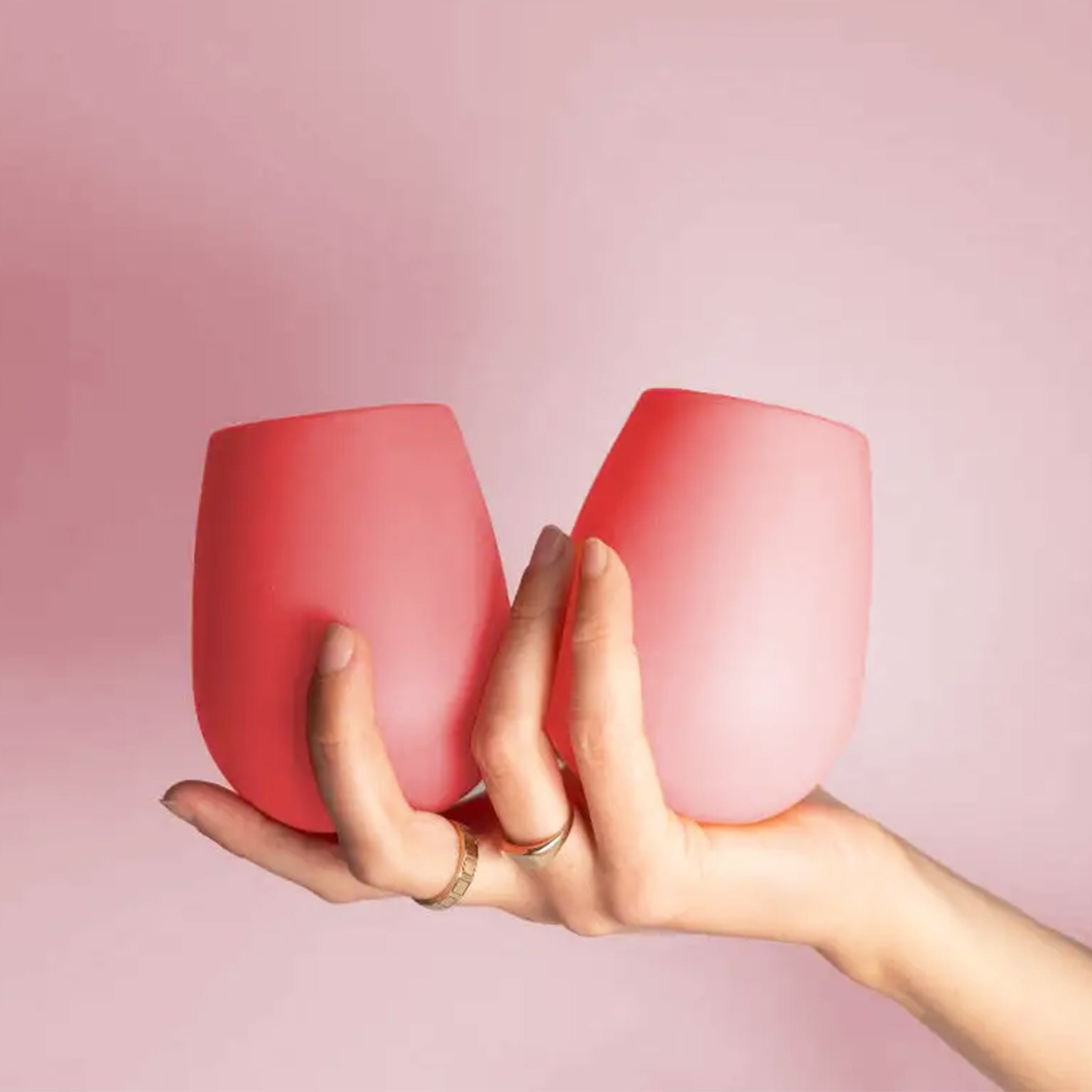 A pair of two pink and peachy silicone stemless wine glasses for on-the-go beverages.