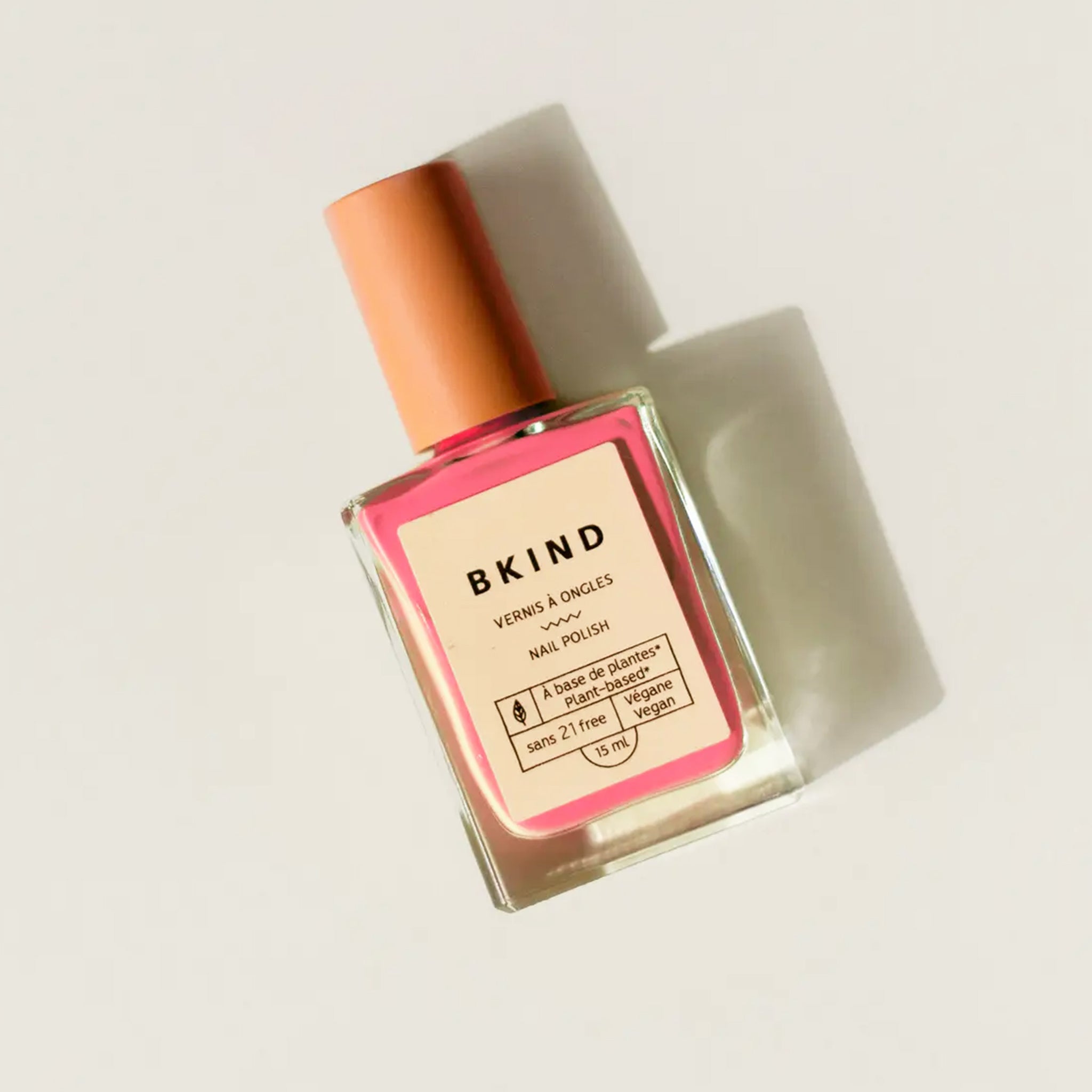 A glass bottle of pink nail polish. 