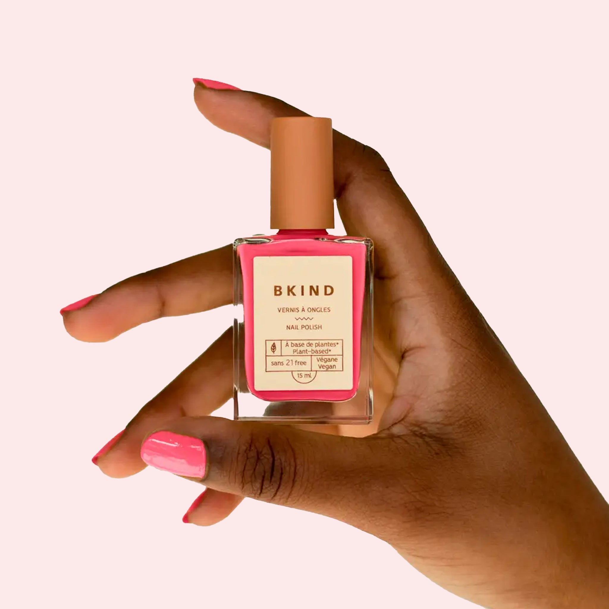 A glass bottle of pink nail polish. 