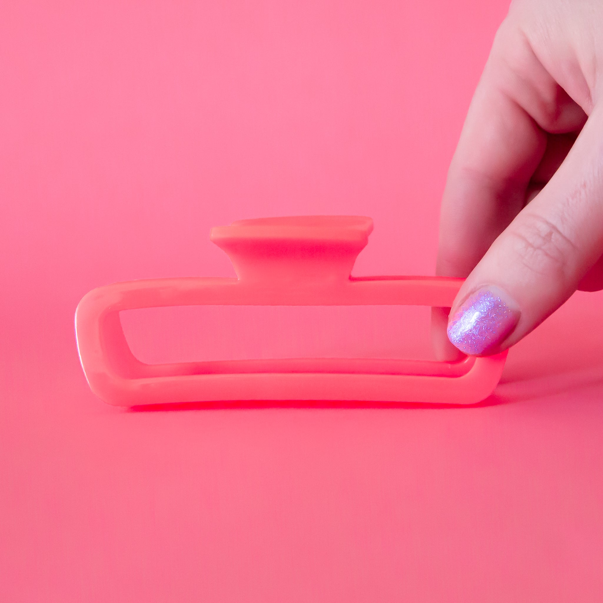 A pink rectangle hair clip with rounded edges. 