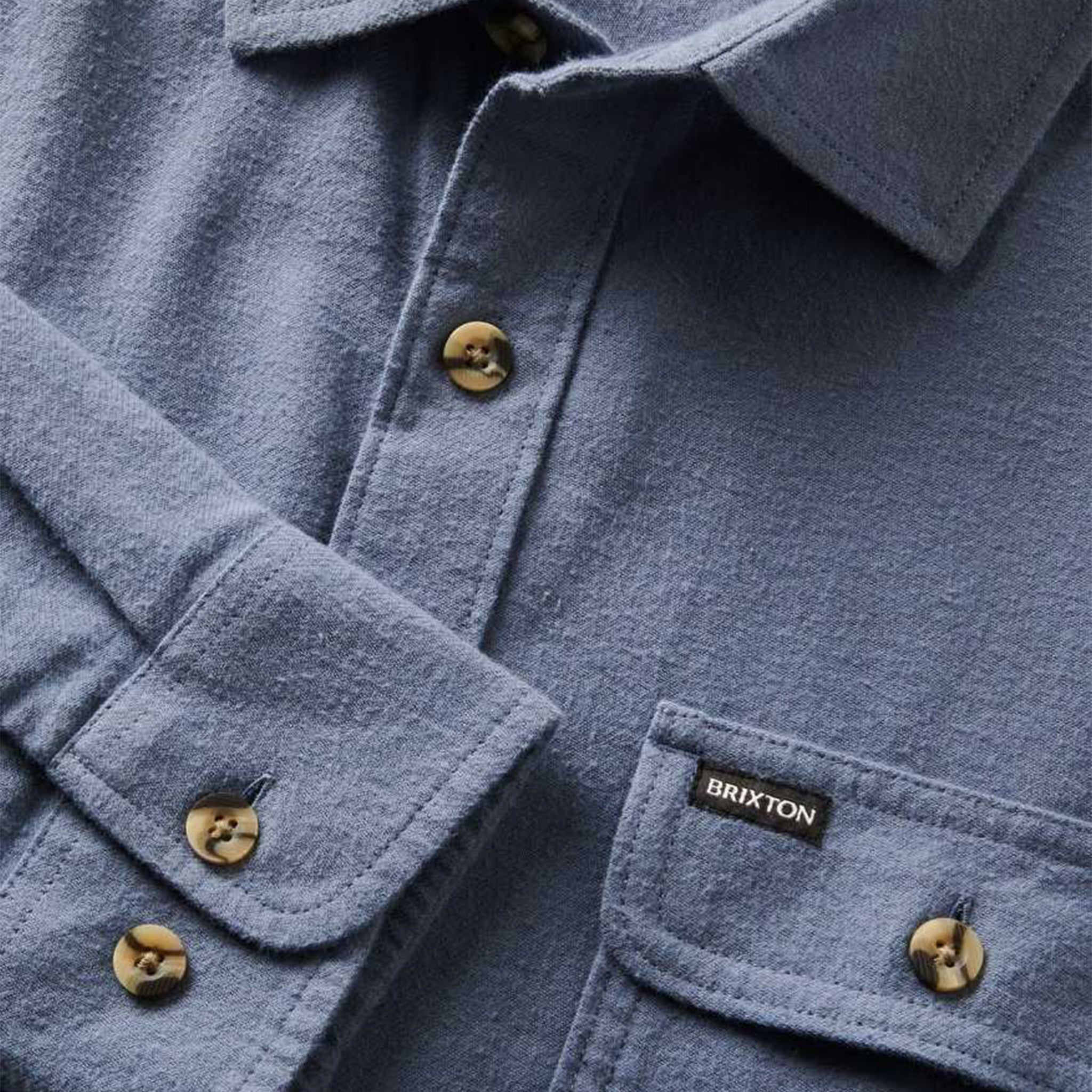 A blue flannel material button up shirt for men with long sleeves and two front pockets.