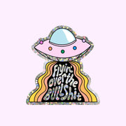 A space ship shaped sticker with multi colored lights and holographic text that reads, 'Flyin' over the Bullshit'. 